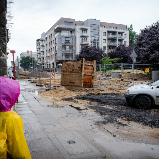 Dziecko w przeciwdeszczowym płaszczu patrzące się na rozkopaną ulicę
